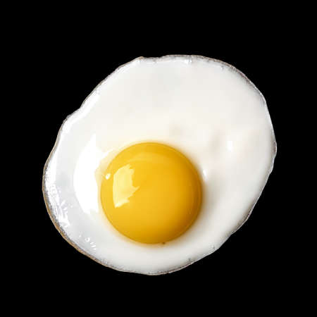 Closeup photo of fried egg isolated on black backgroundの写真素材