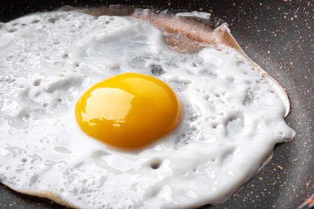 Closeup photo of fried egg on the pan surfaceの写真素材