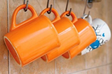 Tea cup orange hang on hooks on the wallの写真素材