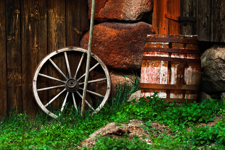 Still-life with an old wheel and barrel standing near the wallの写真素材