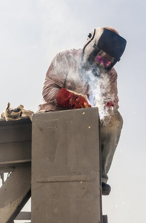 Welder at work, sitting on a metal structureの写真素材