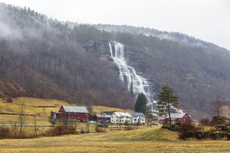 Landscape with a mountain waterfall in early spring near the settlement in Norwayの写真素材