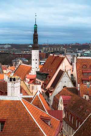 Tallinn, Estonia - The tall tower of the Church of the Holy Spirit surrounded by colorful tiled roofs. View from the observation deck in the old city.の写真素材