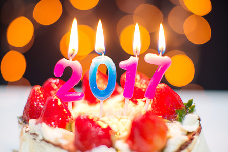 New Year 2017 still life. close up strawberry cake  with burning candles on bokeh background