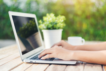 Woman hand using laptop computer on wooden tableの写真素材