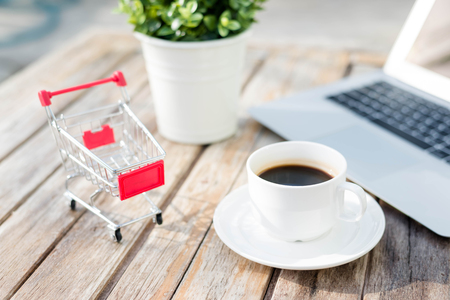 Shopping cart and coffee on wooden table,online shopping conceptの写真素材
