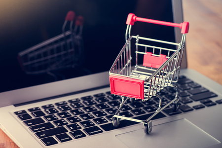 Tablet and shopping cart on wood table, Online shopping conceptの写真素材
