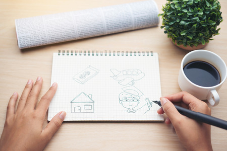 Female hand writing down on letter paper with cup of tea on the wood desk, top viewの写真素材