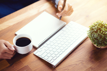 women writing and key board coffee on wooden tableの写真素材