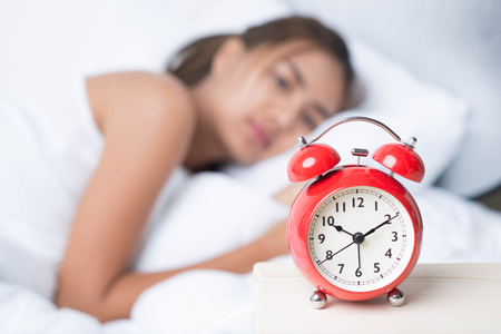 Young sleeping woman and alarm clock in bedroom at home Young sleeping woman and alarm clock in bedroom at home