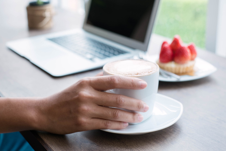 Woman working at home office hand holding coffee cup close up