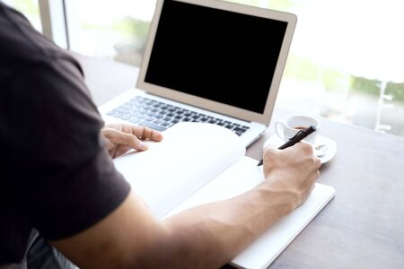 man using laptop and write note inspire idea on wood desk