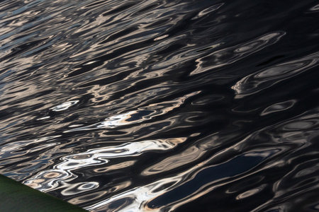 The gliding rays of the sun draw abstract patterns on the wavy surface of the water.の写真素材