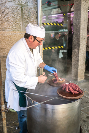 Santiago de Compostela, Spain - December 14, 2013 - Man selling tables of just cooked octopus galician style in the Abastos Market in Santiago de Compostelaのeditorial素材