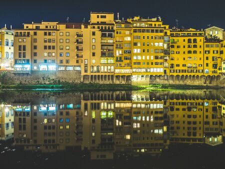 Reflections of the buildings around the Ponte Vecchio (Vecchio Bridge) on the Arno river at nightのeditorial素材