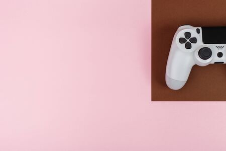 Top view on a gaming joystick lie on pink desk