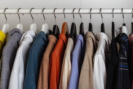 Close-up view of clothes hung on hangers in the dressing room on the white barの写真素材
