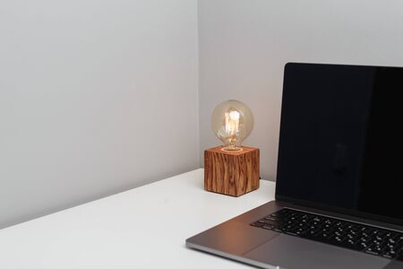 Old-fashioned lamp and a modern laptop on a white tableの写真素材