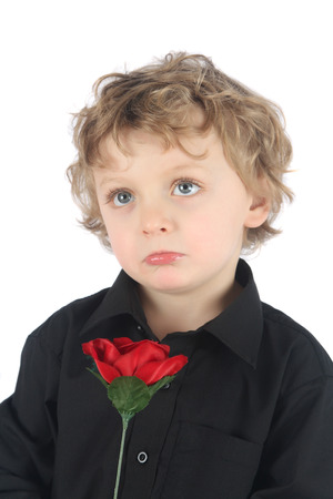 Pouting blonde boy holding a red roseの写真素材