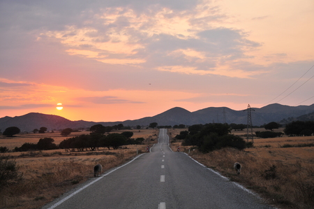 Rural road to the mountains at sunsetの写真素材