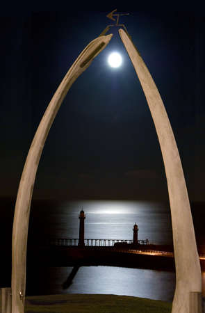 Whitby moonrise over piers seen through whale-bone archway.の写真素材