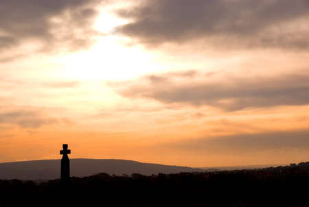 Pink and peach sky over Celtic cross standing in Whitby graveyard, North Yorkshire, England.の写真素材
