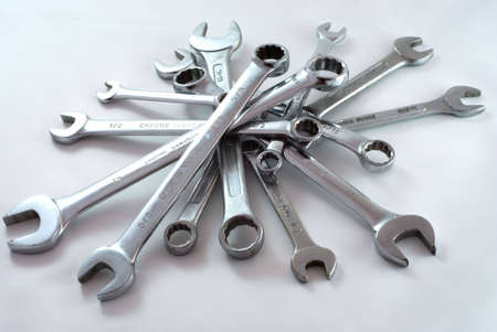 Random pile of chrome spanners of different sizes on a white background.