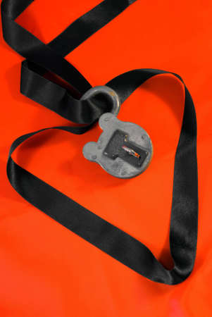 Padlock holding black silk ribbon on red silk background.の写真素材