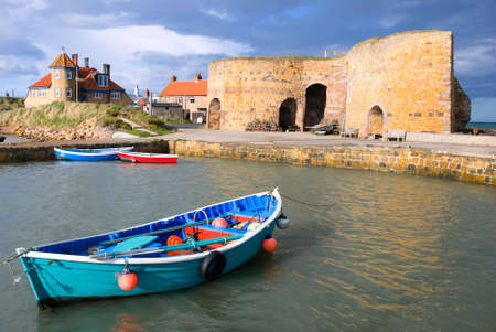 Rowing boat in Northumberland harbour overlooked by lime kilnsの写真素材