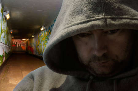 Portrait of man in hoody looking sinister - deliberately darkの写真素材