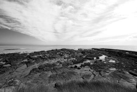 Rocks revealed by receding tide under dramatic skyの写真素材