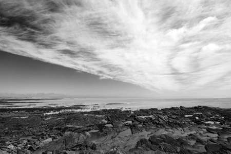 Rocks revealed by receding tide under dramatic skyの写真素材