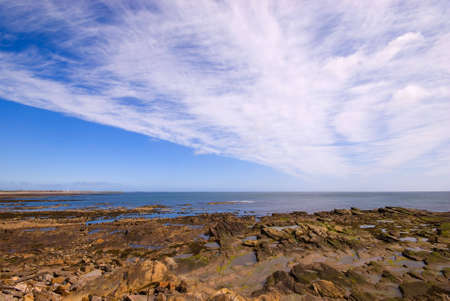 Rocks revealed by receding tide under dramatic skyの写真素材