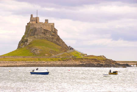 Lindisfarne Castle with boats in Holy Island harbourの写真素材