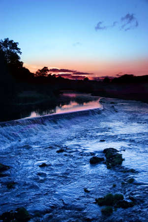 Water running over weir at sunset at Grassington, Yorkshire Dales National Park, North Yorkshire, Englandの写真素材