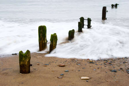 Waves washing over the groins at Sandsend, Whitby, North Yorkshire, England, UKの写真素材