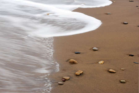 Waves washing over pebbles at Sandsend, Whitby, North Yorkshire, England, UKの写真素材