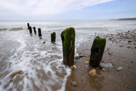 Waves washing over the groins at Sandsend, Whitby, North Yorkshire, England, UKの写真素材