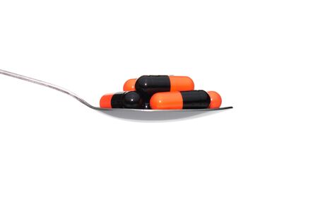 Black orange drug or pill or vitamin on metal Spoon isolated on white background. Concept about health care or medical or science including food concept.の写真素材