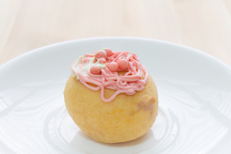 Red choux pastry or cream puff or profiterole that have whipped cream on the head. Eclair dessert on wood table.の写真素材