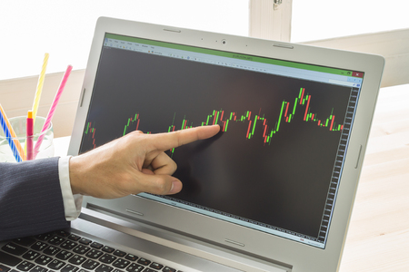 Businessman is pointing stock graph or forex graph . Technical analysis forex or stock by professional traderの写真素材