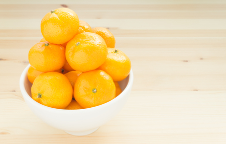 Chinese orange or mandarin or tangerine in white bowl on wood tableの写真素材