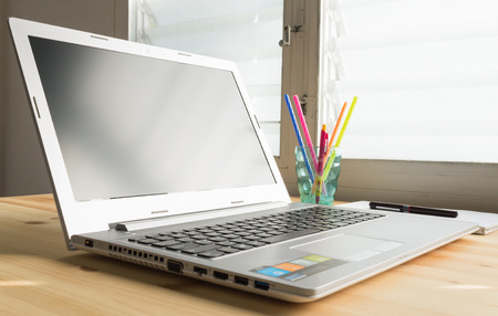 Laptop and notebook and pen and glass on wood table in old office with soft evening light