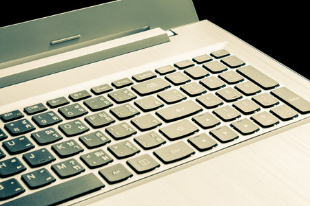 Button of laptop or notebook on black background in dramatic mood in vintage styleの写真素材