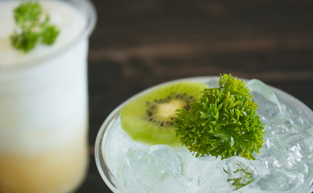 Green Italian Soda Cold Beverage and Kiwi Fruit and Parsley. Green Italian Soda Cold Beverage with Kiwi fruit and ice in glass on wood table. Green Italian Soda with Kiwi for food 
and drink categoryの写真素材