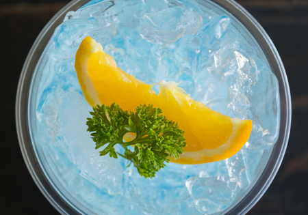 Blue Italian Soda Cold Beverage and Lemon Fruit and Parsley. Blue Italian Soda Cold Beverage with Lemon fruit and ice in glass on wood table for food and drink categoryの写真素材