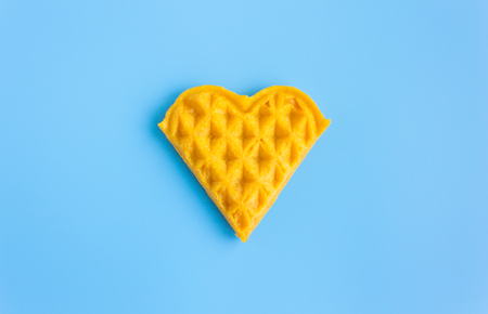 1 Piece Heart Shape Waffle on Blue Pastel Background Minimalist Style. Heart shape waffle dessert in minimalist style for food and dessert categoryの写真素材