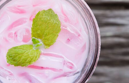 Pink Cold Milk Beverage or Cold Drinks and Peppermint Flatlay Left Frame. Pink cold drinks and ice on wood table for drinkの写真素材