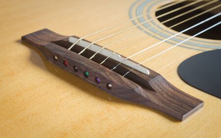 Wood Bridge and Saddle and Pick guard and Sound Hole with Acoustic Guitar String in Natural Light