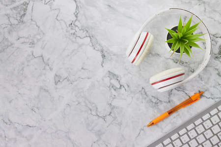 Modern Clean Flat Lay or Top View Office Desk or Office Table and Office Supplies as Computer Keyboard,Pen,Headphone,Office Plants on Marble Minimalist Backgroundの写真素材